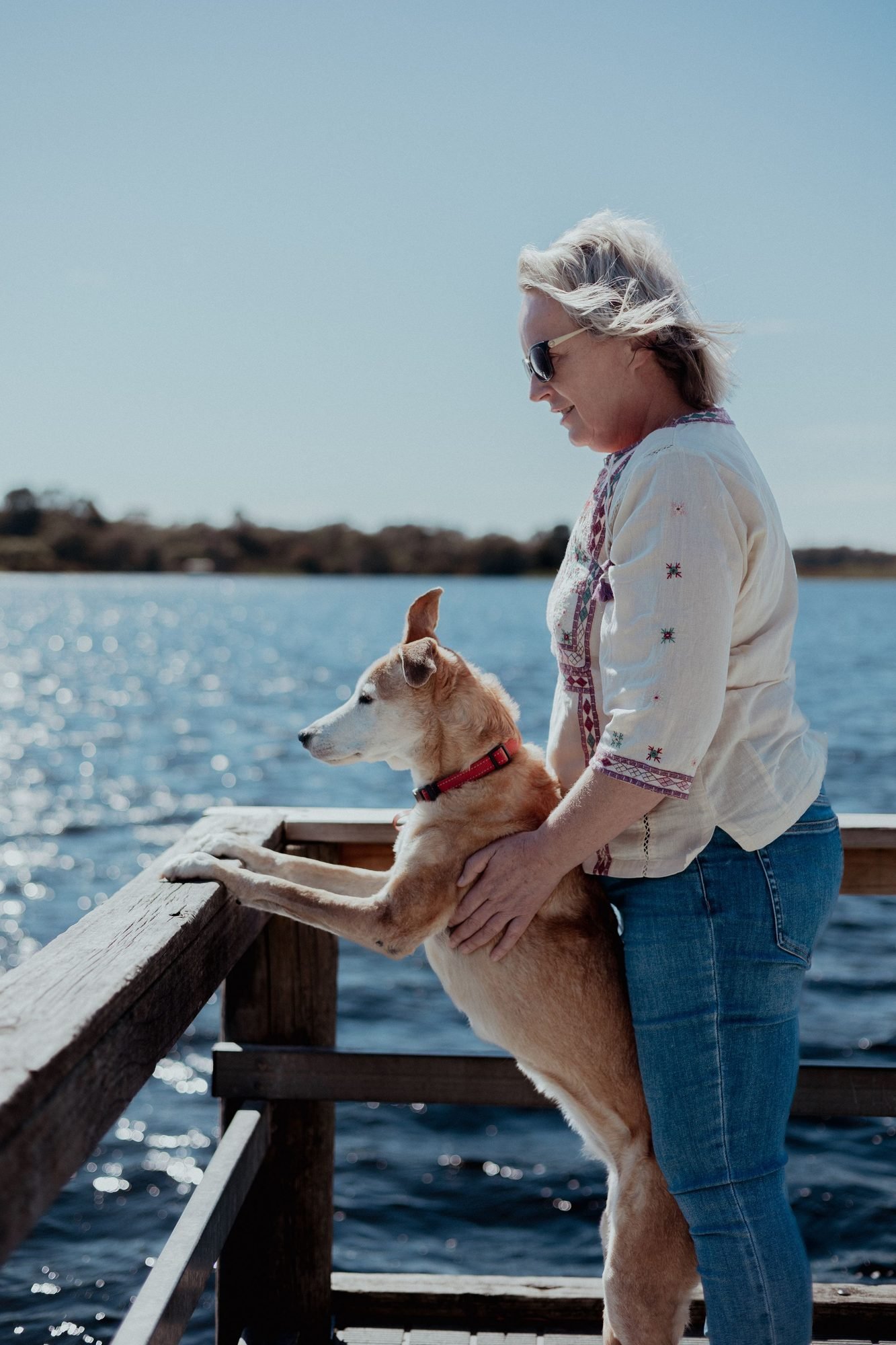 Pet parent and dog looking out over a lake